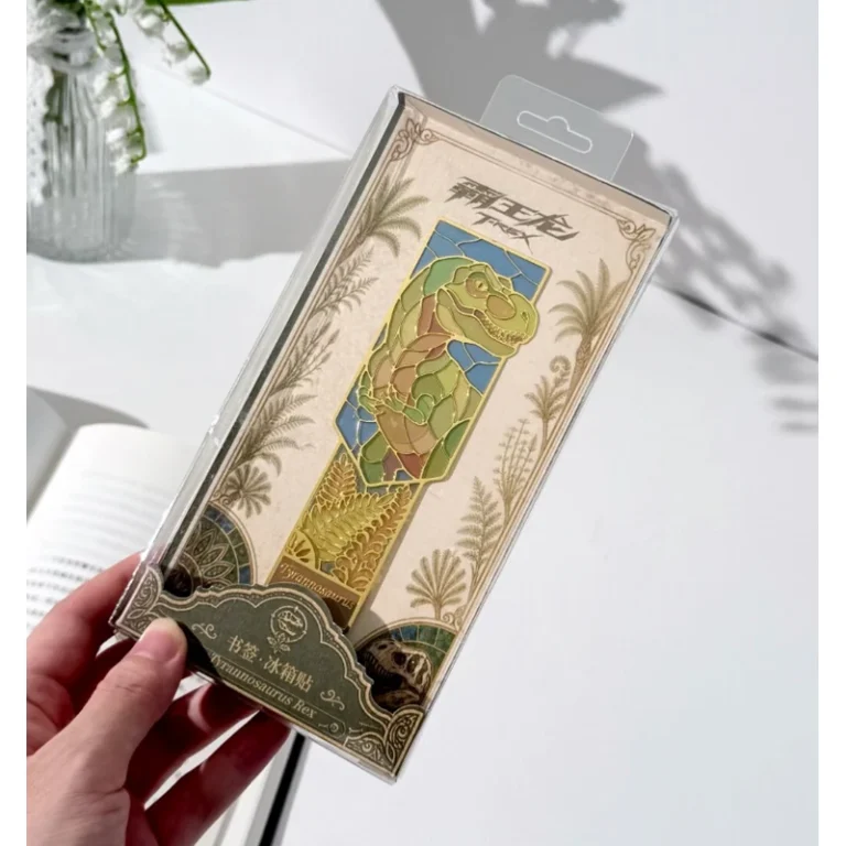 Green and gold-tone character metal bookmark in a decorative retail sleeve, held in a hand.