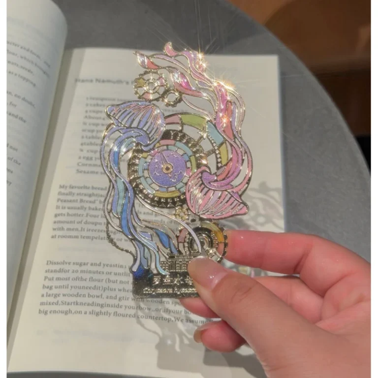 Colorful ornamental enamel metal bookmark with flowing circular patterns held over an open book.