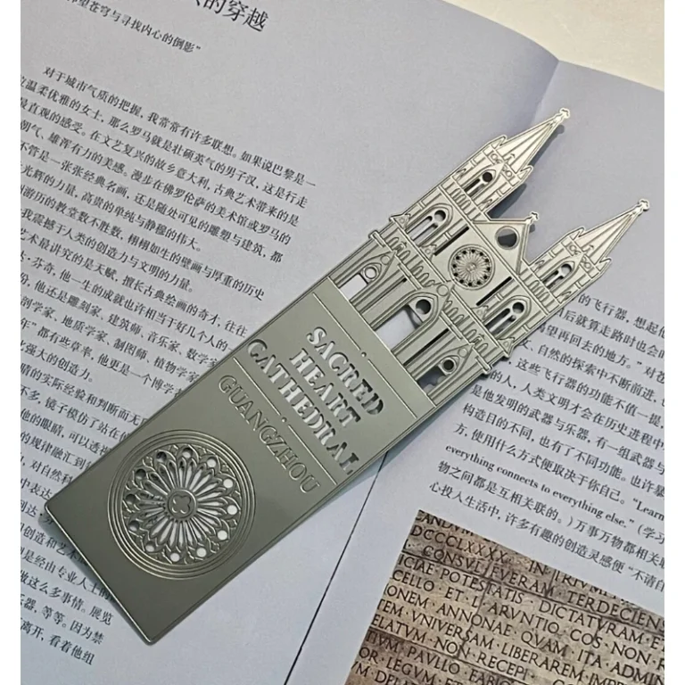 Silver-tone metal bookmark with cathedral towers and a rose window relief placed on a book.
