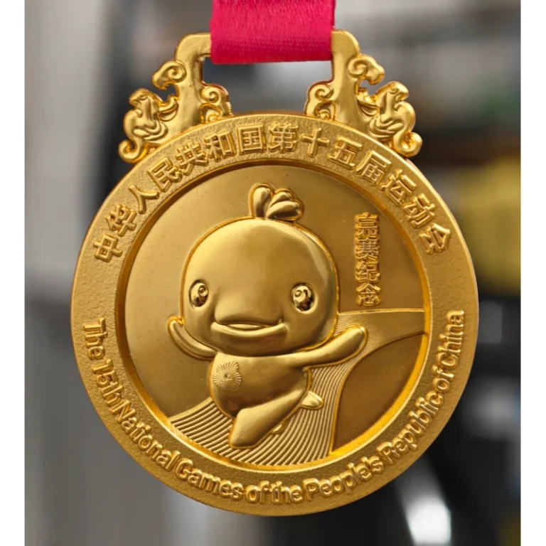 Gold-tone event medal with a mascot relief and red ribbon.