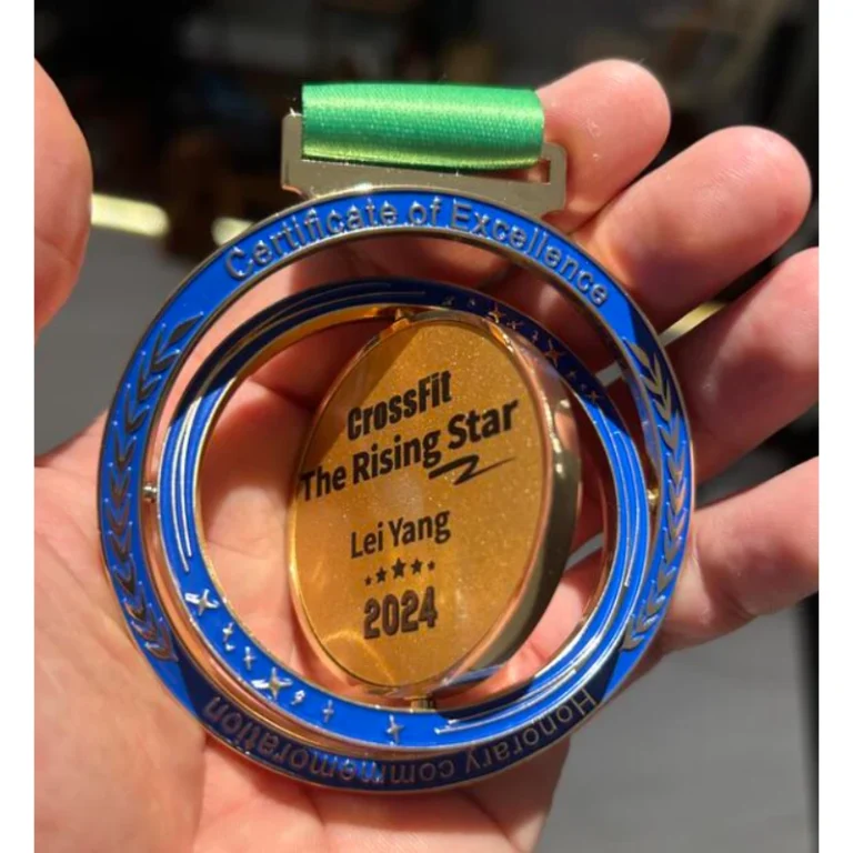 Blue and gold-tone rotating custom medal with a green ribbon, held in a hand.