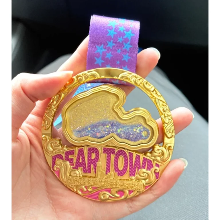 Gold-tone custom medal with star details and a purple ribbon, held in a hand.