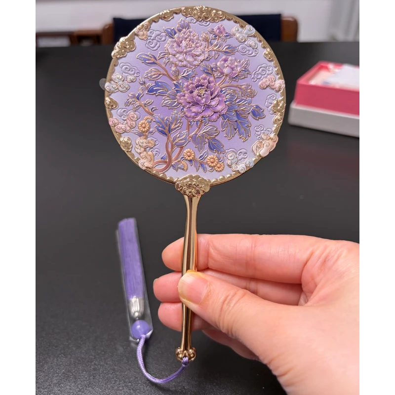 Purple floral enamel handheld mirror with sculpted branches and a matching tassel.