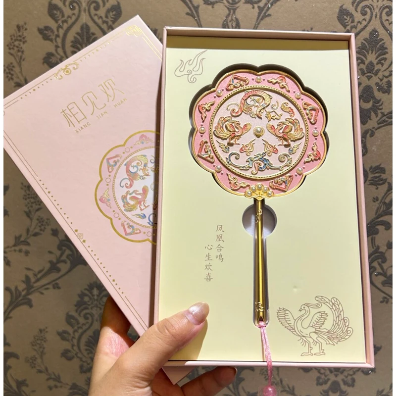 Pink and gold-tone handheld mirror displayed in a pale green presentation gift box.