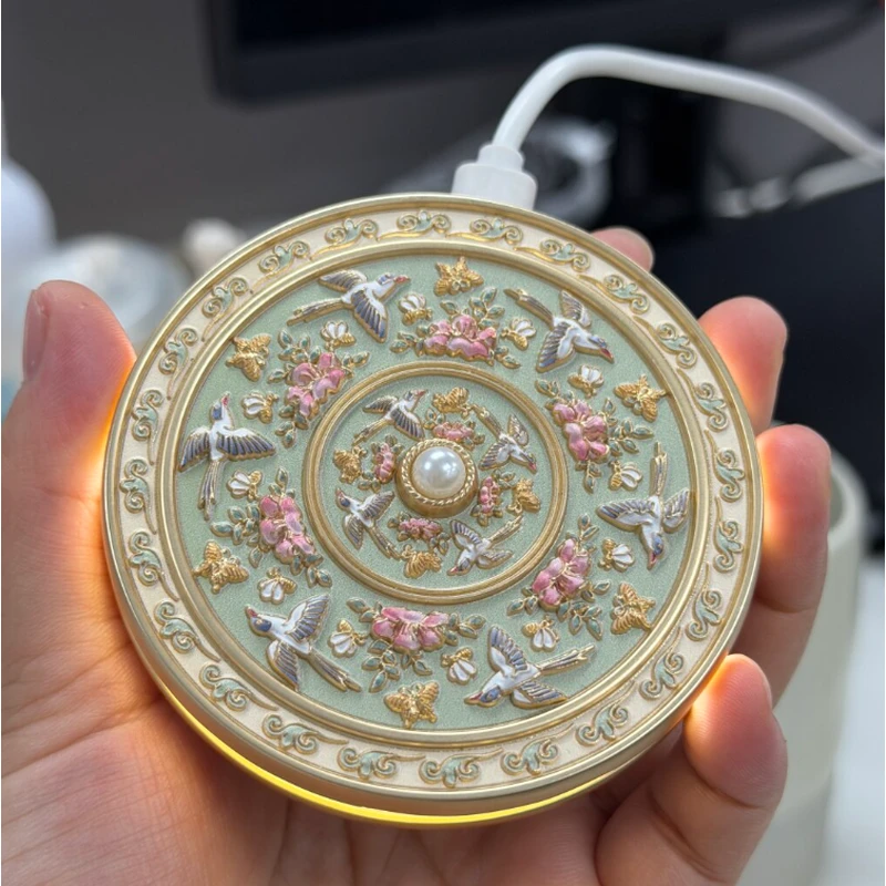 Green round enamel compact mirror with floral relief and pearl details, held in a hand.