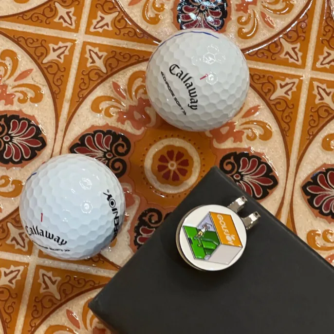 Golf hat clip with magnetic marker and golf balls for scale